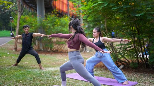 Free Group practicing yoga in a Jakarta park, focusing on balance and flexibility. Stock Photo