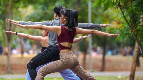 Free Adults practicing yoga together outdoors in Jakarta park. Stock Photo
