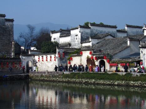 Scenic view of Hongcun Village with traditional buildings and red lanterns along the canal.