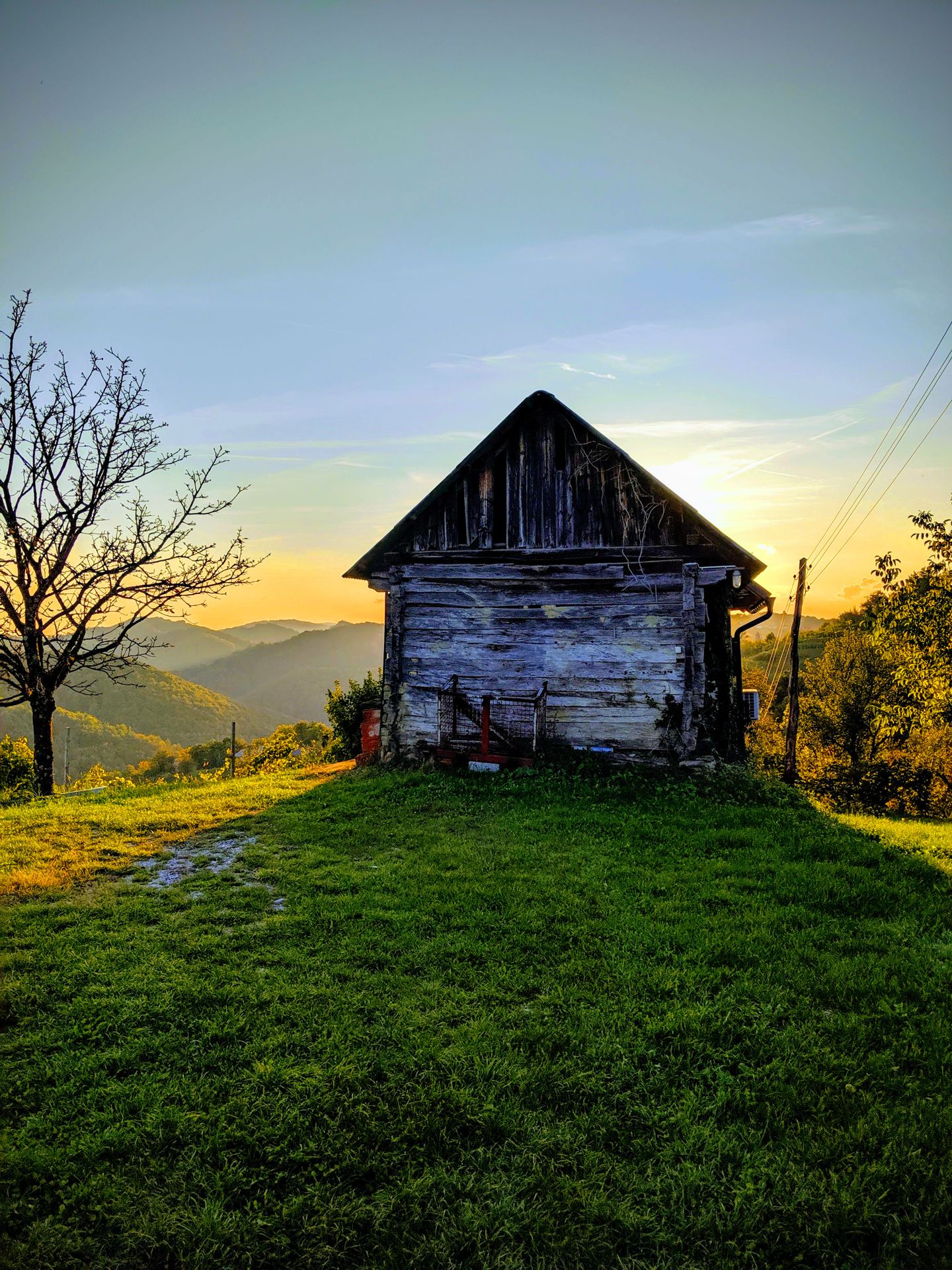 A farmhouse in the Slovenian countryside at sunrise, surrounded by green hills