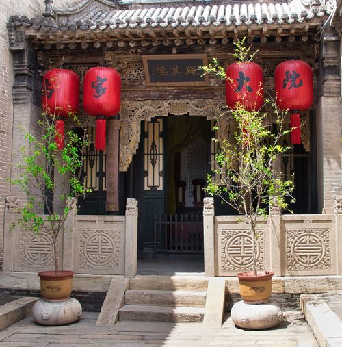 Free Classic Chinese courtyard entrance with red lanterns and ornate decorations. Stock Photo