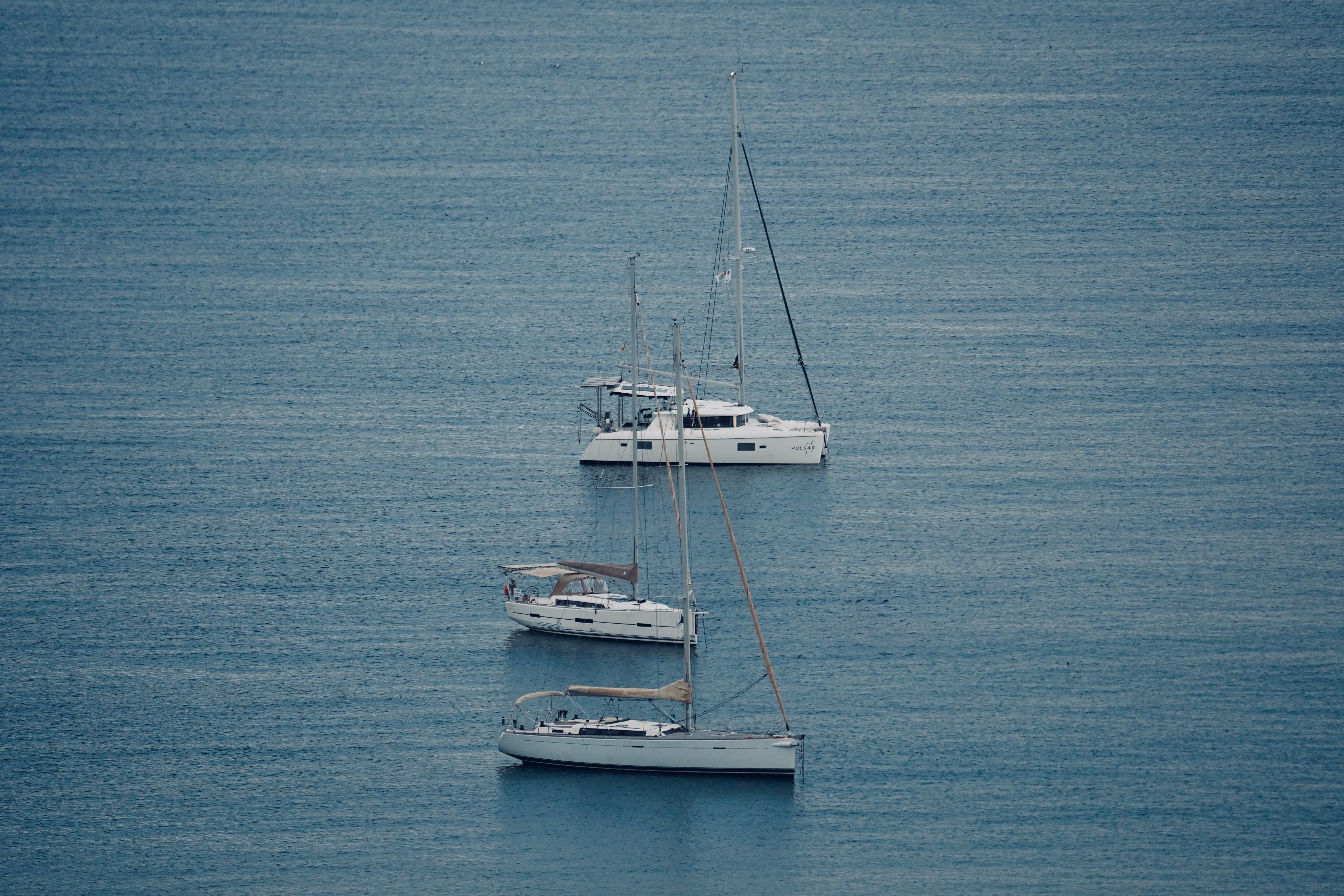 Peaceful scene of yachts floating on calm blue waters, ideal for travel and leisure concepts.