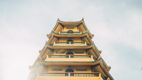 Free Stunning view of a traditional Asian pagoda with vibrant yellow hues against a bright sky. Stock Photo