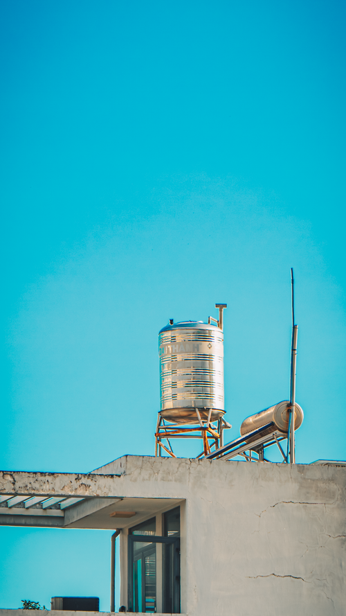 Free Metal water tank on a rooftop with a clear blue sky backdrop Stock Photo