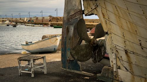Free Old boat and propeller by a calm harbor, showcasing rustic maritime charm. Stock Photo
