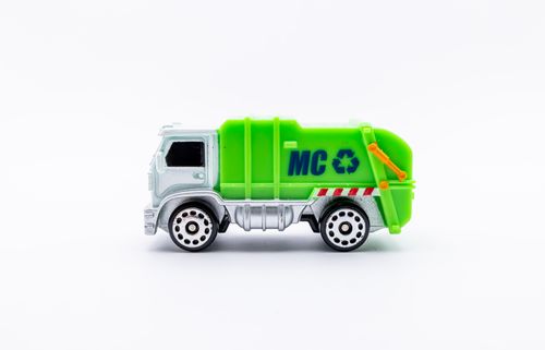 Free Close-up of a toy green garbage disposal truck on a minimalist white background. Stock Photo