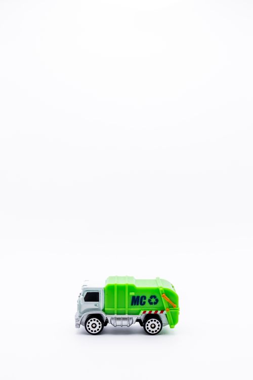 Free Green toy garbage truck on white background with ample copy space, emphasizing recycling concept. Stock Photo