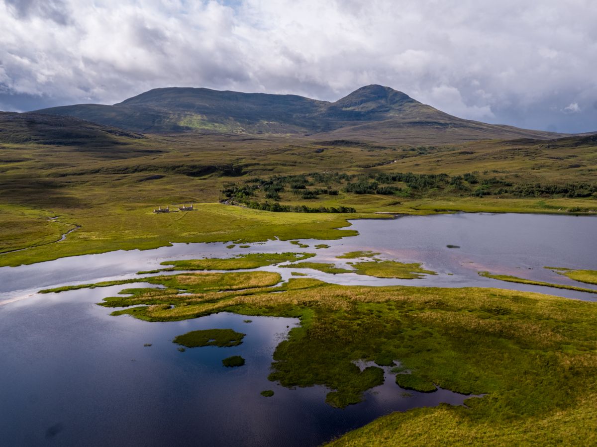 Aerial view of Scottish Highlands hills, lochs and misty valleys under a dramatic sky, illustrative photo