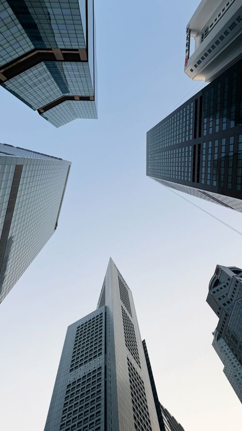 Free Looking up at modern skyscrapers in Singapore's urban skyline against a clear blue sky. Stock Photo