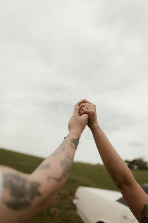 Free Two tattooed hands clasped together in an outdoor setting, symbolizing unity and connection. Stock Photo