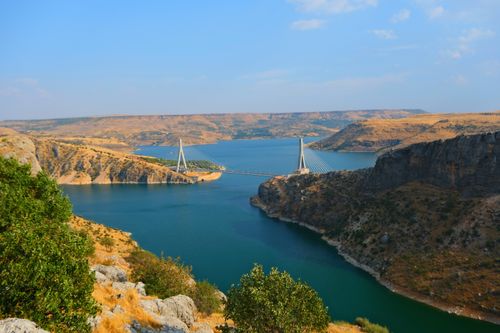 Free Breathtaking view of the Euphrates Bridge spanning over a shimmering river in a desert landscape. Stock Photo