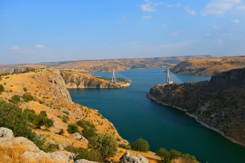 Free Scenic view of the Nissibi Bridge spanning the Euphrates River amid rocky landscapes under a clear sky. Stock Photo