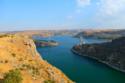 Free A breathtaking view of a bridge spanning a canyon with turquoise water and rocky cliffs, captured on a sunny day. Stock Photo