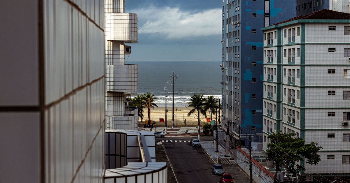 Modern apartment buildings overlooking a beach under a cloudy sky.