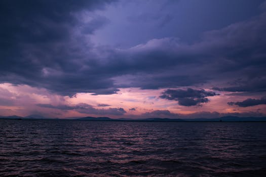 Stunning view of a dramatic twilight sky with clouds over a calm ocean, casting vibrant colors.