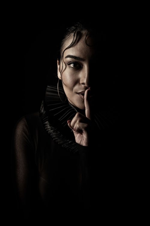 Free Dramatic chiaroscuro portrait of a woman signaling silence. Stock Photo