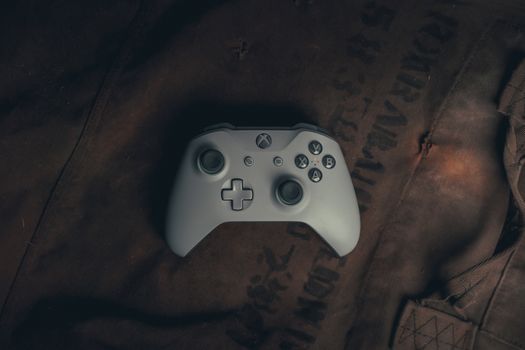 Top view of a gaming controller on rustic fabric, evoking a vintage gaming vibe.