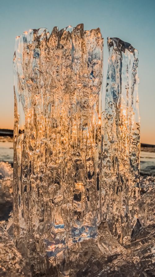 Free Stunning ice sculpture captures sunlight during a spring sunset by the river, showcasing nature's artistry. Stock Photo