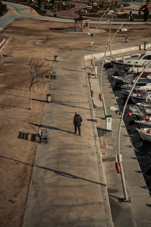 Unrecognizable man walking on embankment near motor boats in port