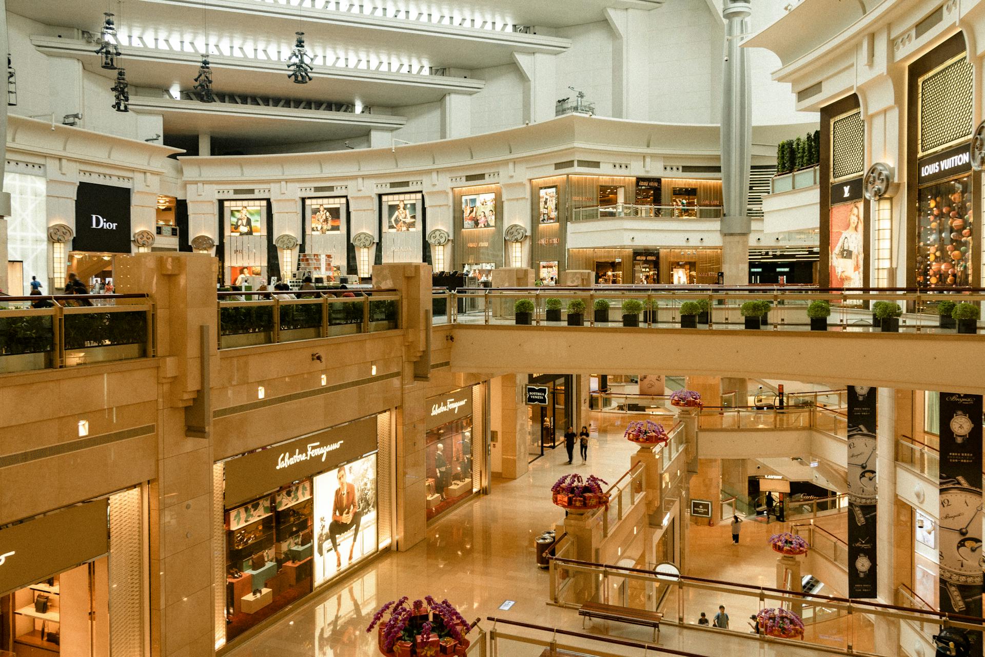 Contemporary design of big mall interior with ribbed column and decorative elements on ceiling with glowing corridors illuminated by artificial lights and signboards with inscriptions