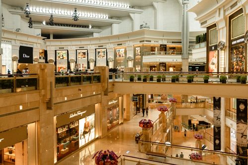 Free Contemporary design of big mall interior with ribbed column and decorative elements on ceiling with glowing corridors illuminated by artificial lights and signboards with inscriptions Stock Photo