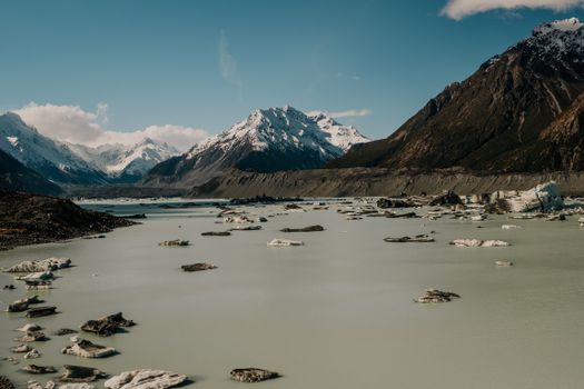 Breathtaking view of snow-capped mountains and glacial lake at Tasman Glacier, New Zealand.