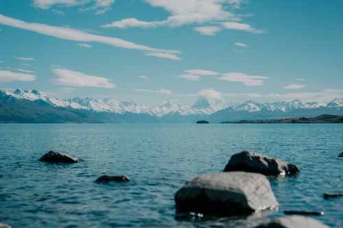 Free Tranquil lake with snowy mountains in New Zealand under a bright sky. Stock Photo