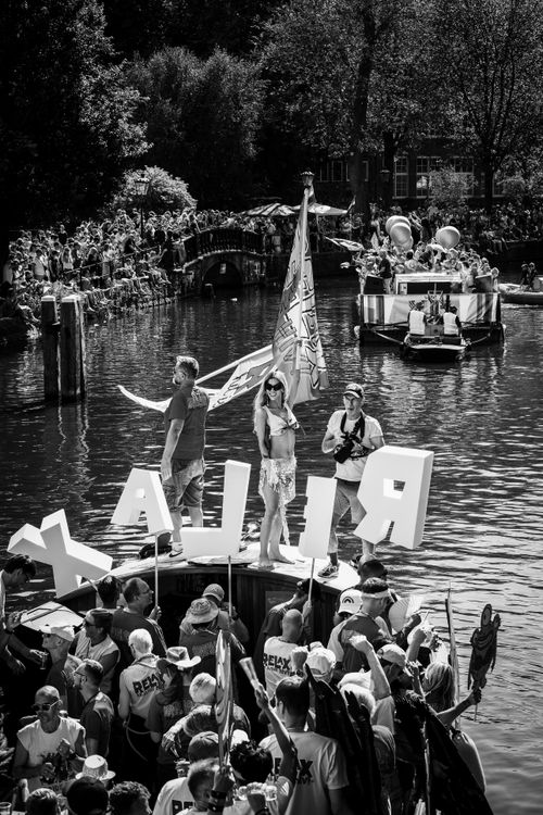 Free Lively canal parade in Amsterdam with decorated boats and festive crowds. Stock Photo