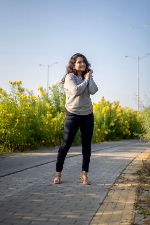 Free A cheerful woman enjoys a walk on a sunny day in India, surrounded by vibrant yellow flowers. Stock Photo