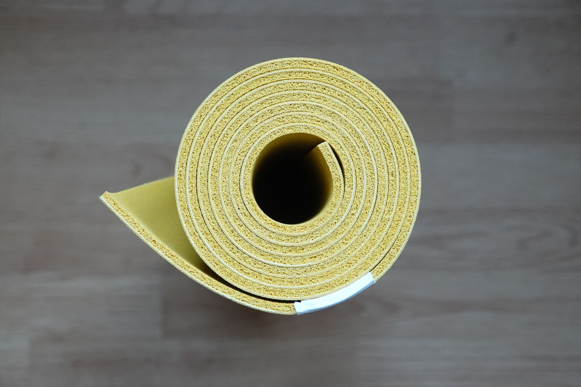 健身器材新手入門指南:選購使用全攻略 Close-up of a rolled yellow yoga mat, ideal for fitness enthusiasts and interior design.