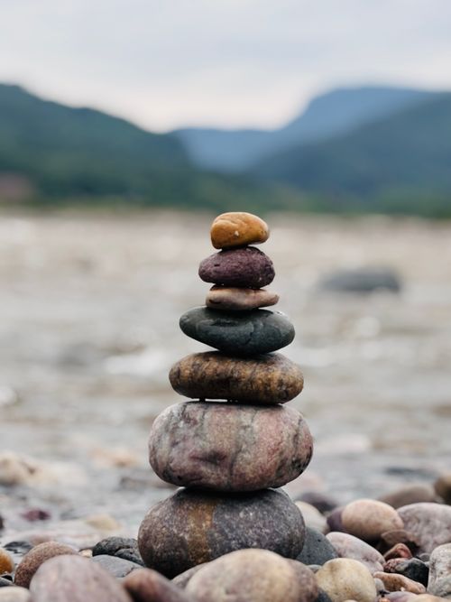 Free Stack of balanced stones with mountain backdrop, symbolizing tranquility. Stock Photo