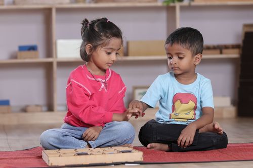 Free Two children exploring a Montessori educational activity indoors, fostering collaborative learning. Stock Photo