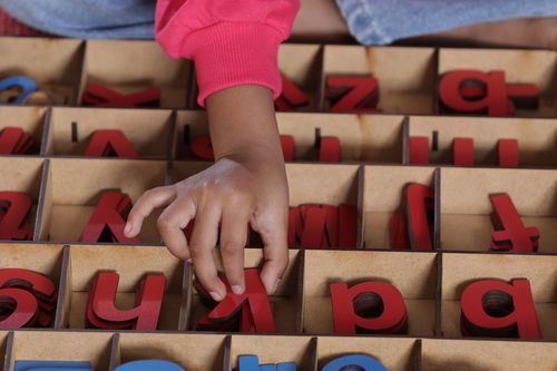 Free A child arranges colorful wooden alphabet letters, enhancing early literacy skills. Stock Photo