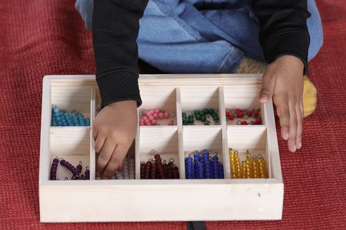 Free Child engaging with Montessori bead material for math learning. Stock Photo