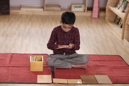 Free A child immersed in Montessori floor activity with learning cards on a red mat indoors. Stock Photo