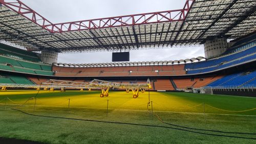 Free Wide-angle view of San Siro Stadium field, showcasing seating and lighting equipment inside the iconic venue. Stock Photo