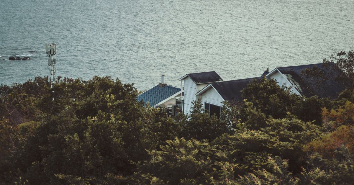 A serene coastal house nestled among lush greenery with a view of the ocean.