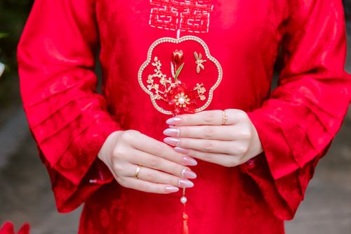 Free Woman in elegant traditional red dress holding a decorative fan, showcasing fine craftsmanship. Stock Photo