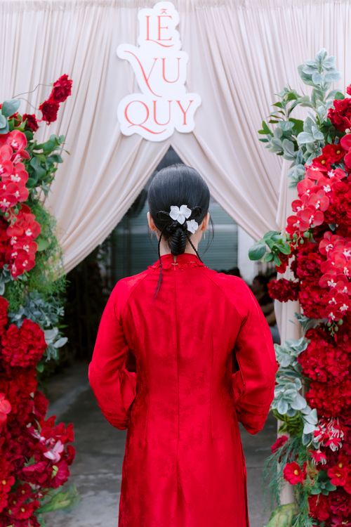 Free A woman in a red dress at a Vietnamese wedding entrance with floral decorations. Stock Photo