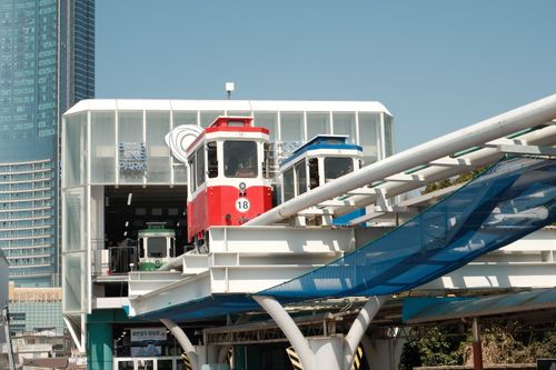 Free Aerial view of vibrant urban monorail station set against towering skyscraper backdrop. Stock Photo