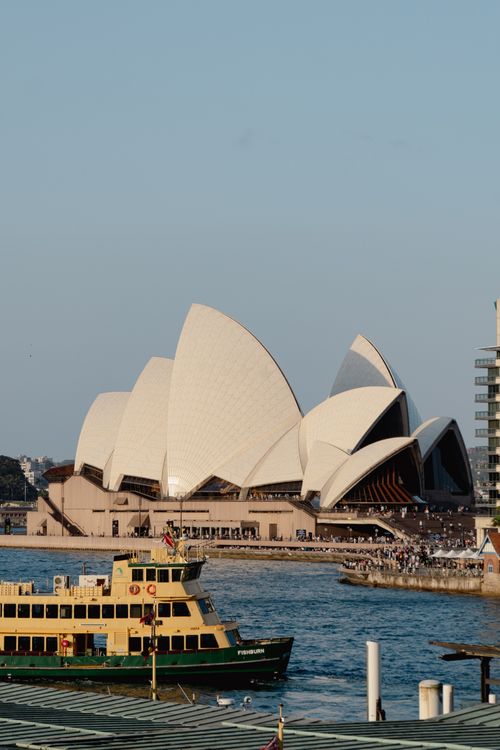 Free Sydney Opera House with a ferry in the harbor. Iconic Australian landmark at day. Stock Photo