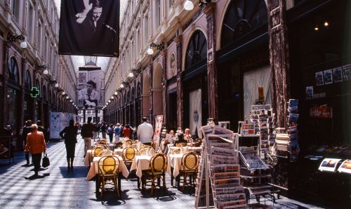 Free Bustling European shopping arcade with café seating and magazine stands. Stock Photo