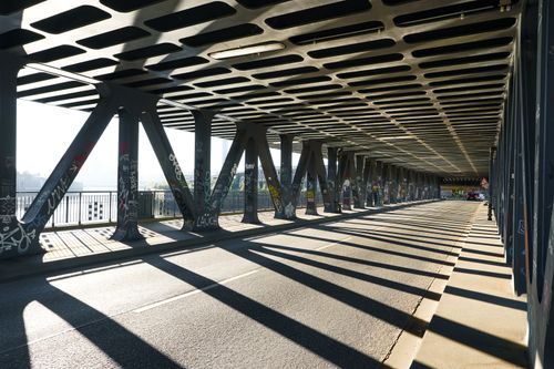 Free Sunlit steel bridge in Hamburg with dramatic shadow play and urban graffiti art. Stock Photo