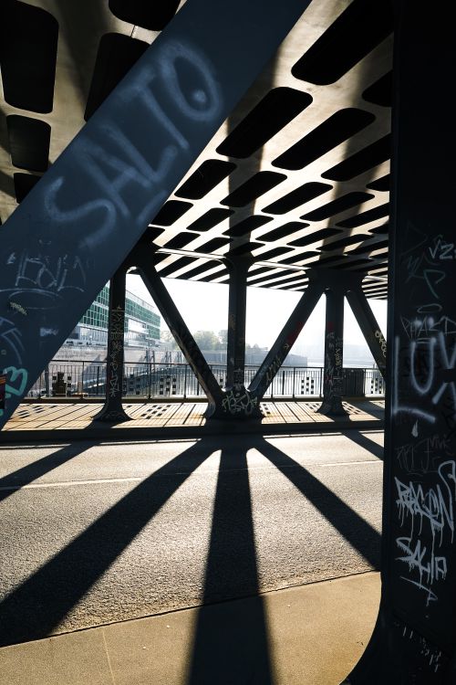 Free Dramatic shadows cast by a steel bridge in Hamburg during daylight with graffiti. Stock Photo