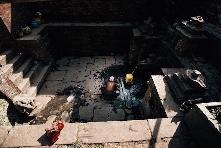 Unrecognizable Ethnic Man Collecting Water From Stone Well