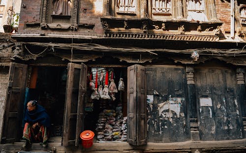 Unrecognizable poor ethnic man sitting on old wooden house porch