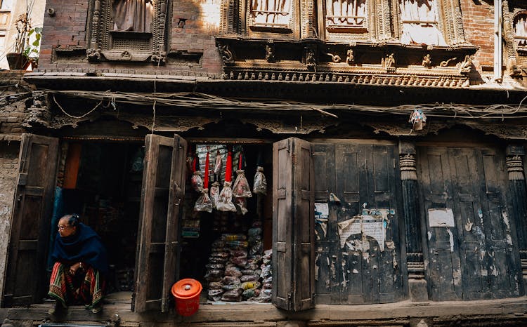 Unrecognizable Poor Ethnic Man Sitting On Old Wooden House Porch