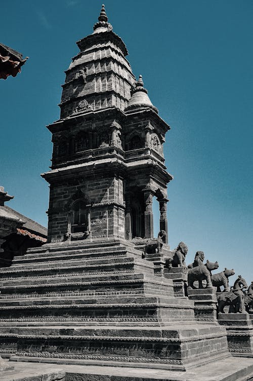 From below of aged masonry church facade with stairs and statues of animals under cloudless sky in daylight in Bhaktapur