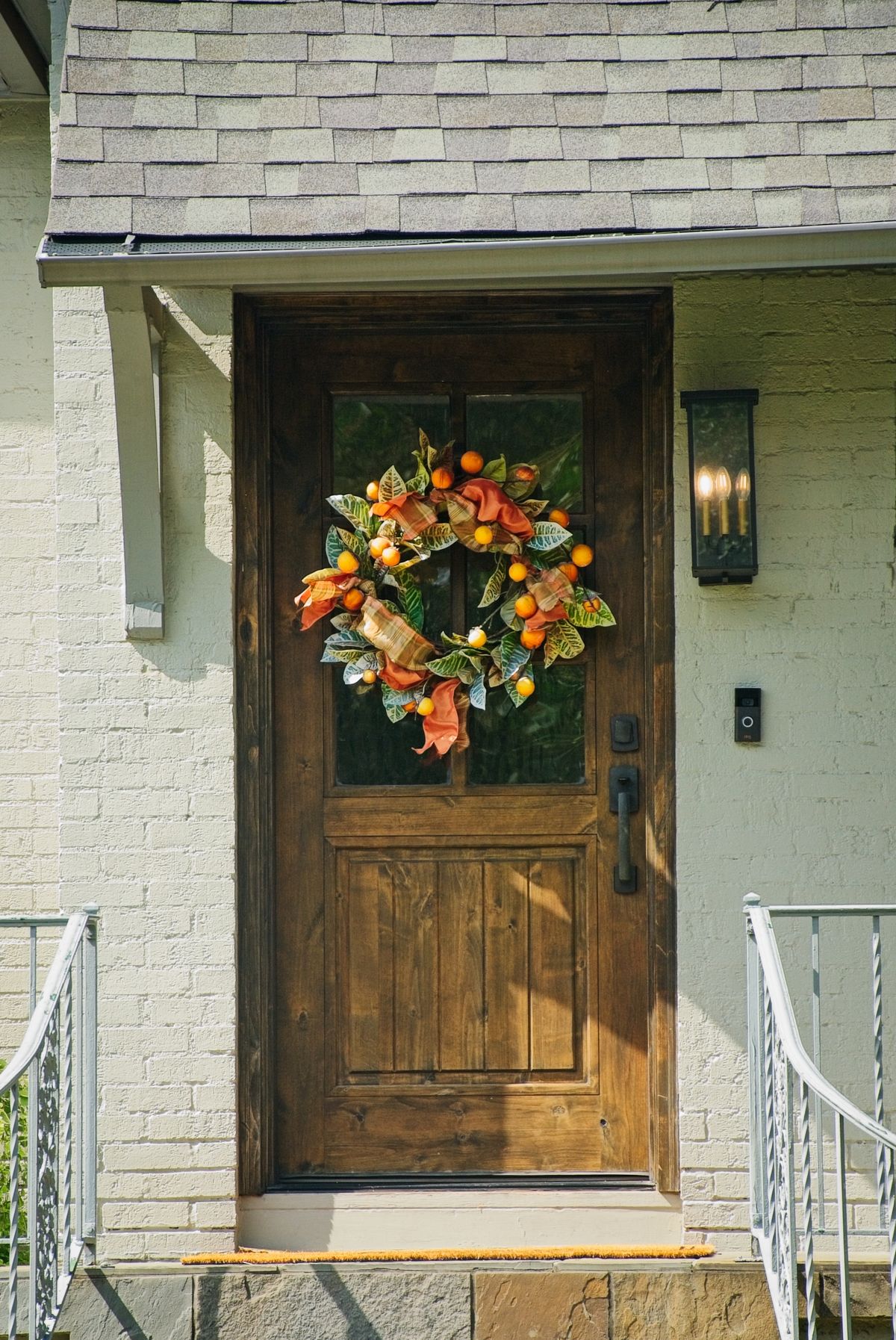 A cozy suburban home entrance decorated for autumn with a vibrant wreath. Stock Photo.