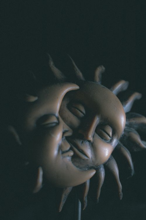 Free Creative design of embracing moon and sun with closed eyes and content faces with beams on edges made of clay as symbol of day and night on black background Stock Photo